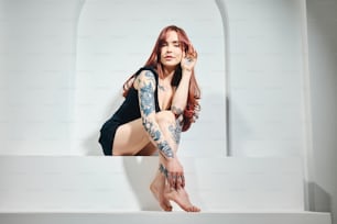 una donna con tatuaggi seduta su una sporgenza