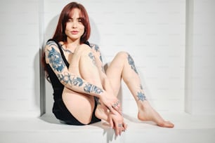 una donna con tatuaggi seduta sul pavimento
