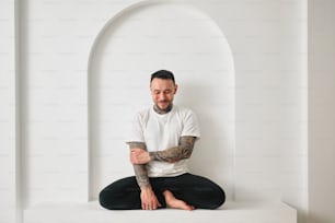 a man with tattoos sitting in a white room