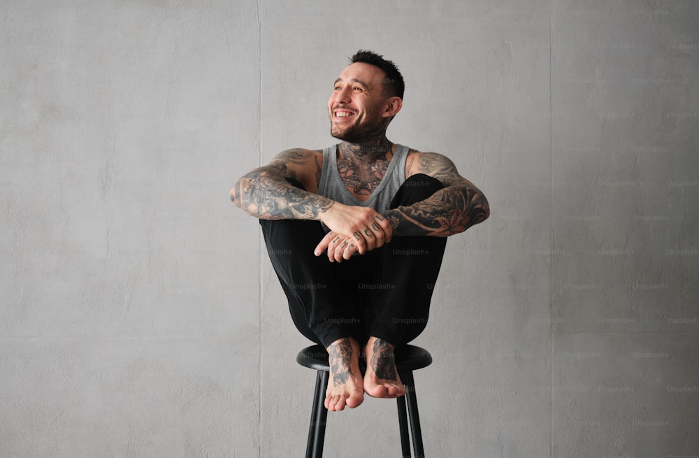 a man with tattoos sitting on a stool