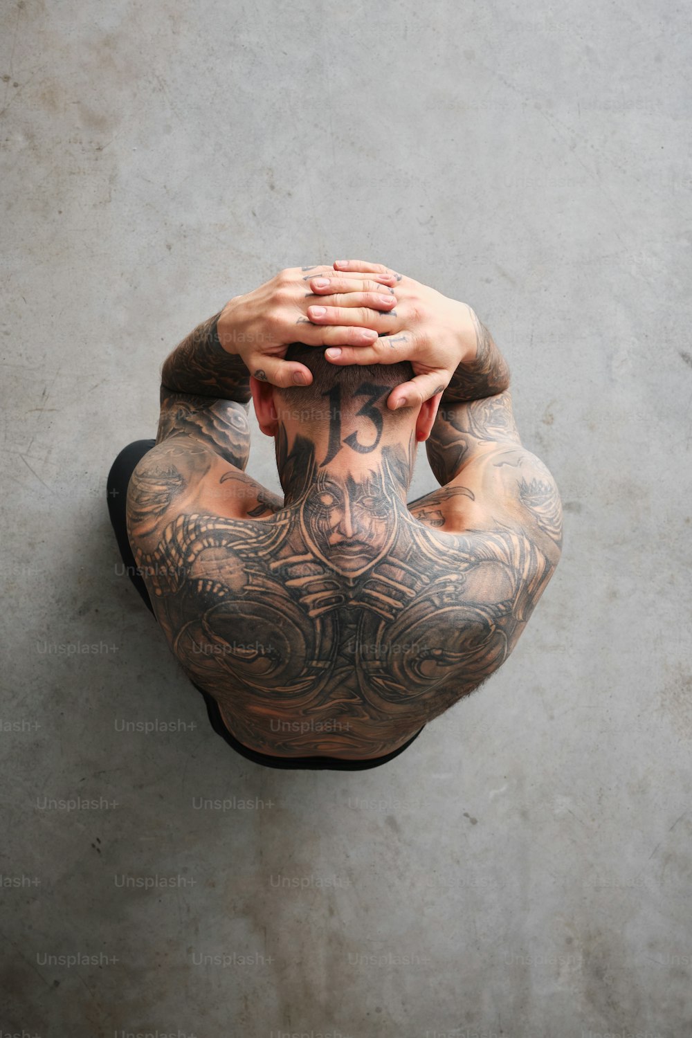 a man with tattoos on his back holding his hands to his face