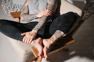 Un hombre con tatuajes sentado en una silla