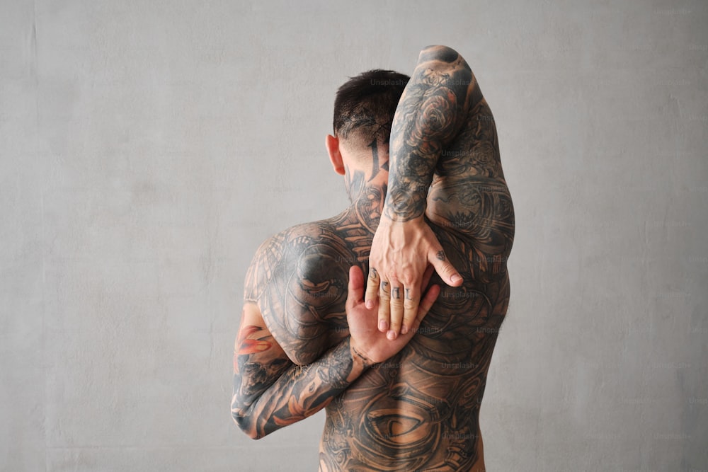Un hombre con tatuajes en el cuerpo sosteniendo el brazo de otro hombre