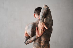 a man with tattoos on his body holding another man's arm