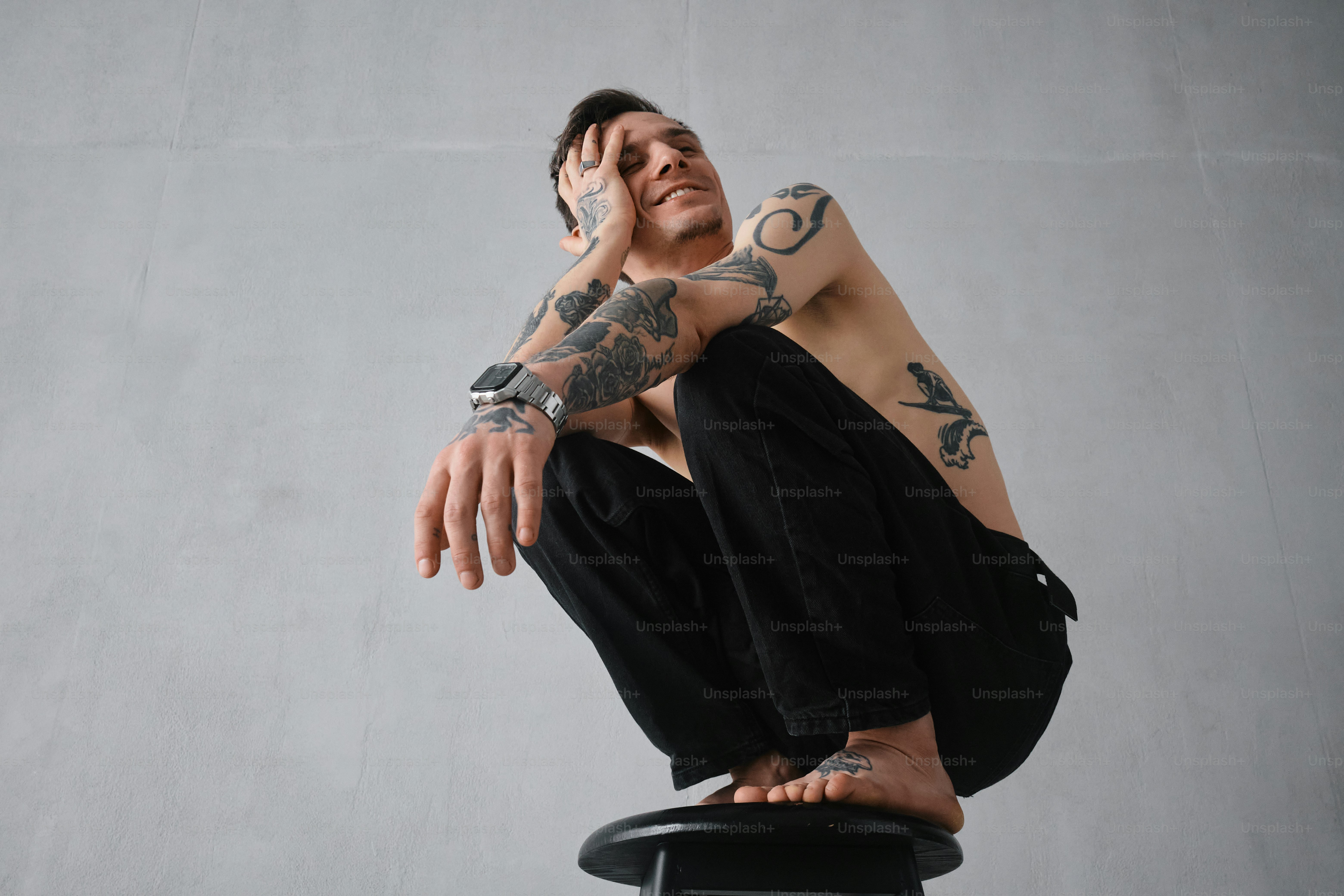 a man with tattoos sitting on a chair