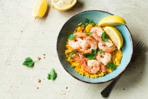 a bowl of shrimp and rice with lemon wedges