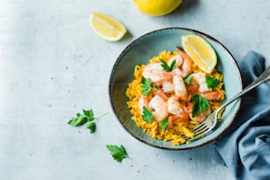 a bowl of shrimp and rice with lemons and parsley