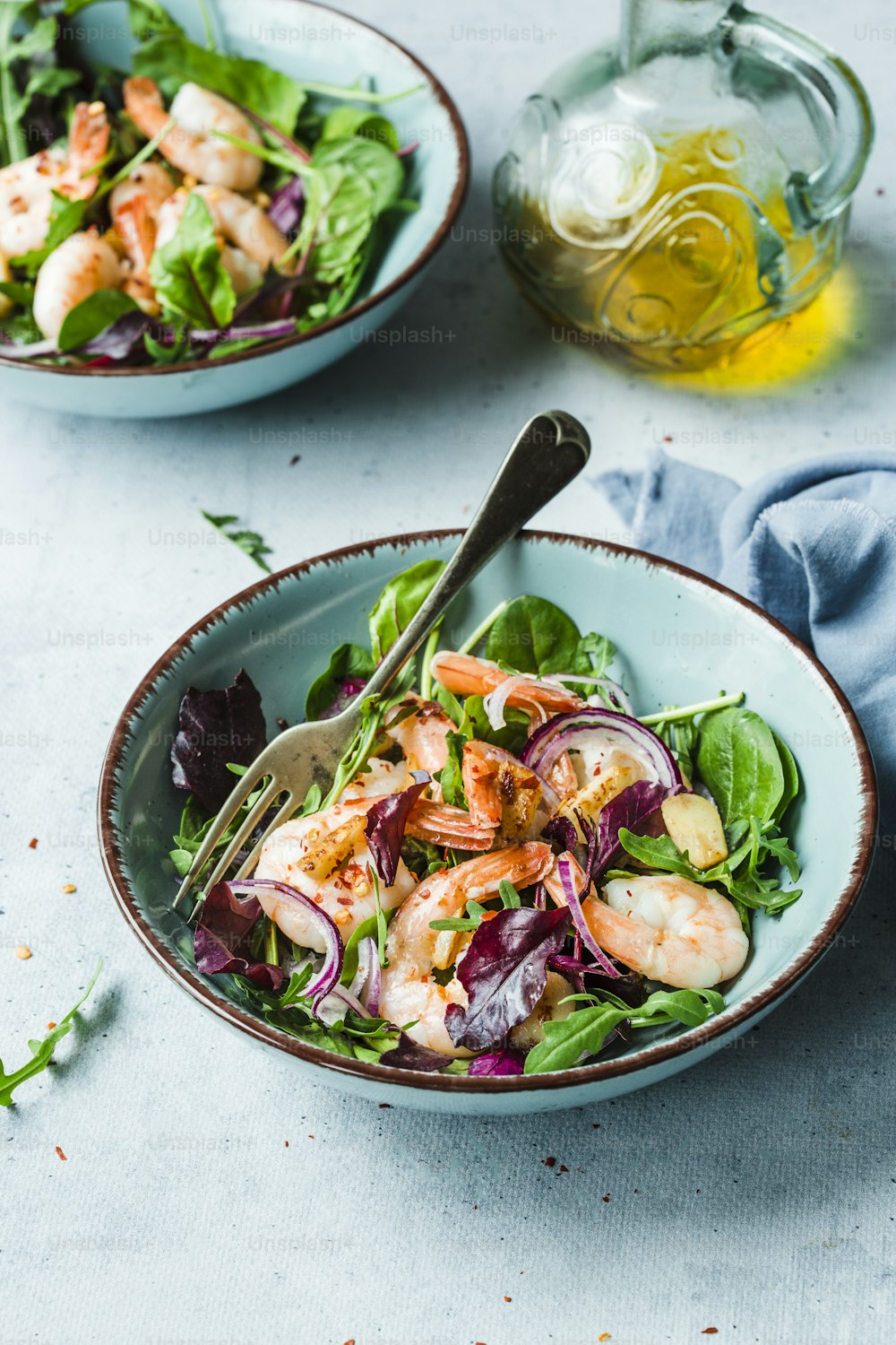 two bowls of salad with shrimp and greens