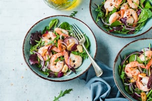three bowls of salad with shrimp and greens