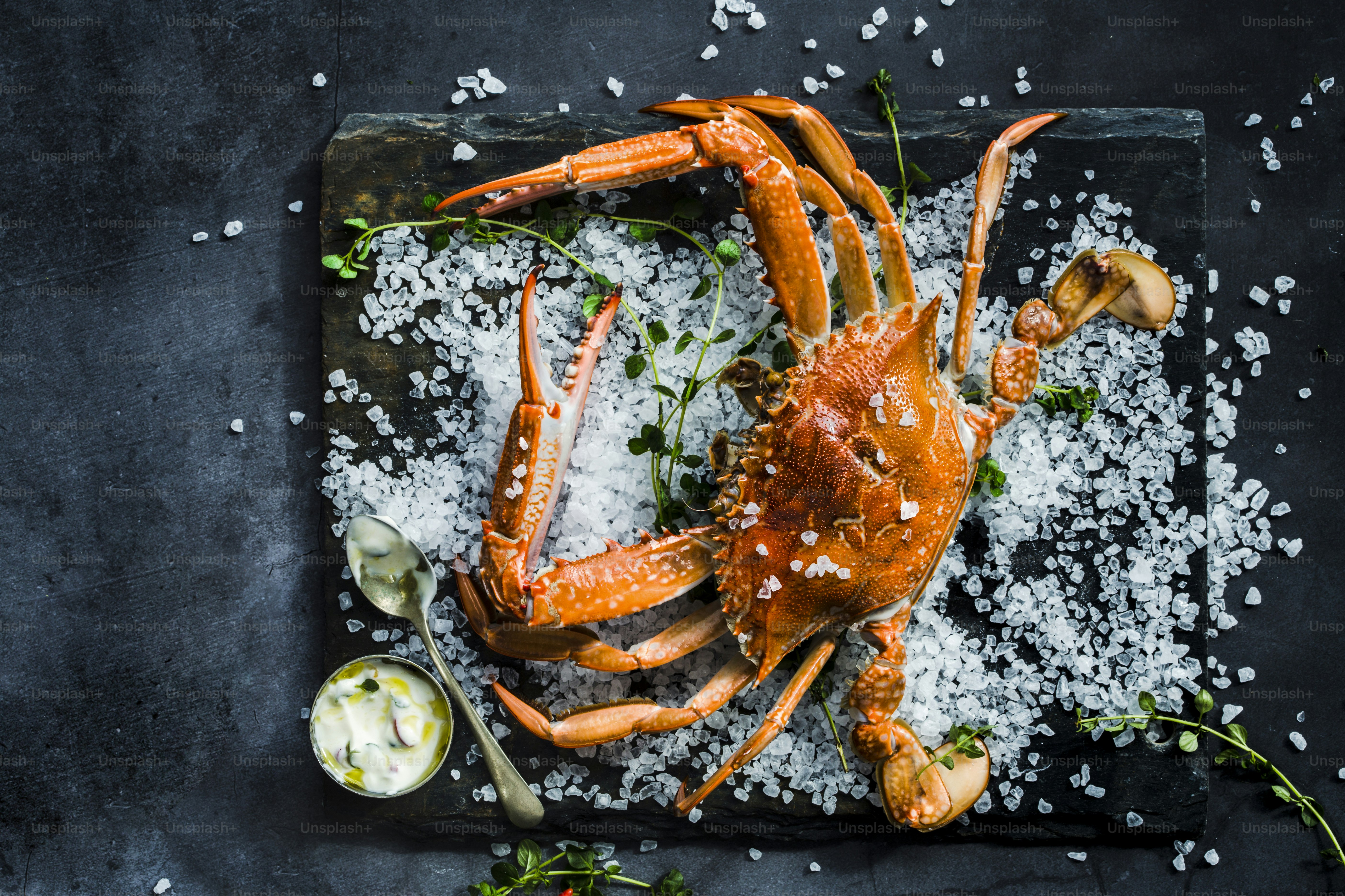 スプーンで黒い皿に調理されたカニ