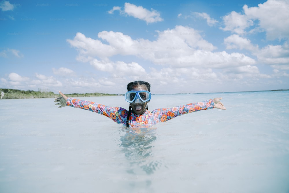 a woman wearing a colorful shirt and goggles in the ocean