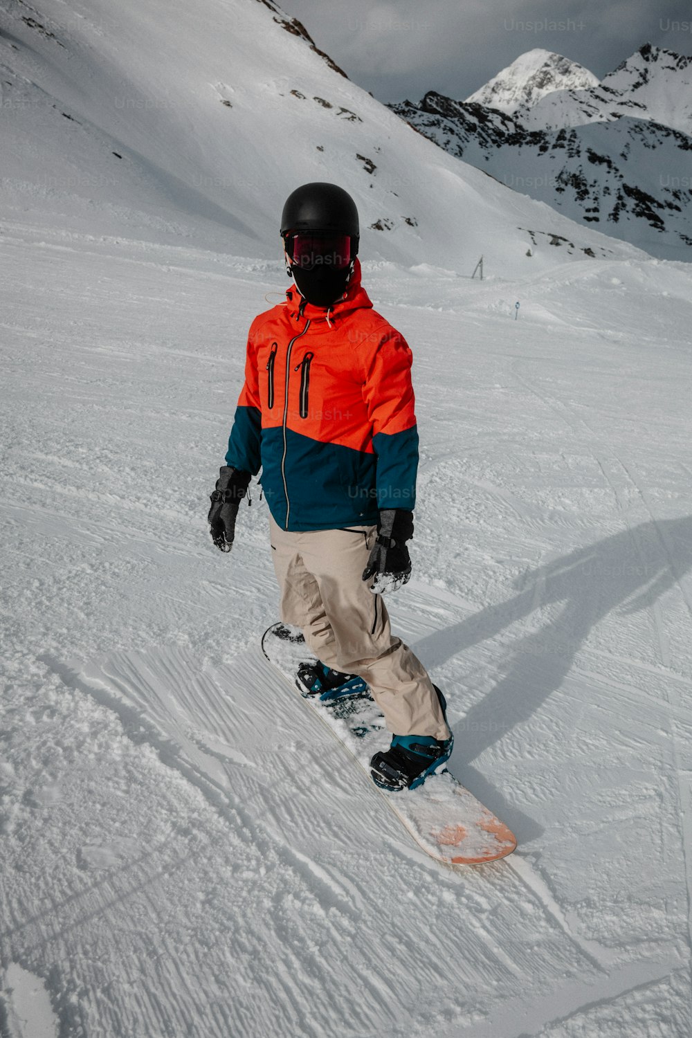 Un hombre montando una tabla de snowboard por una pendiente cubierta de nieve