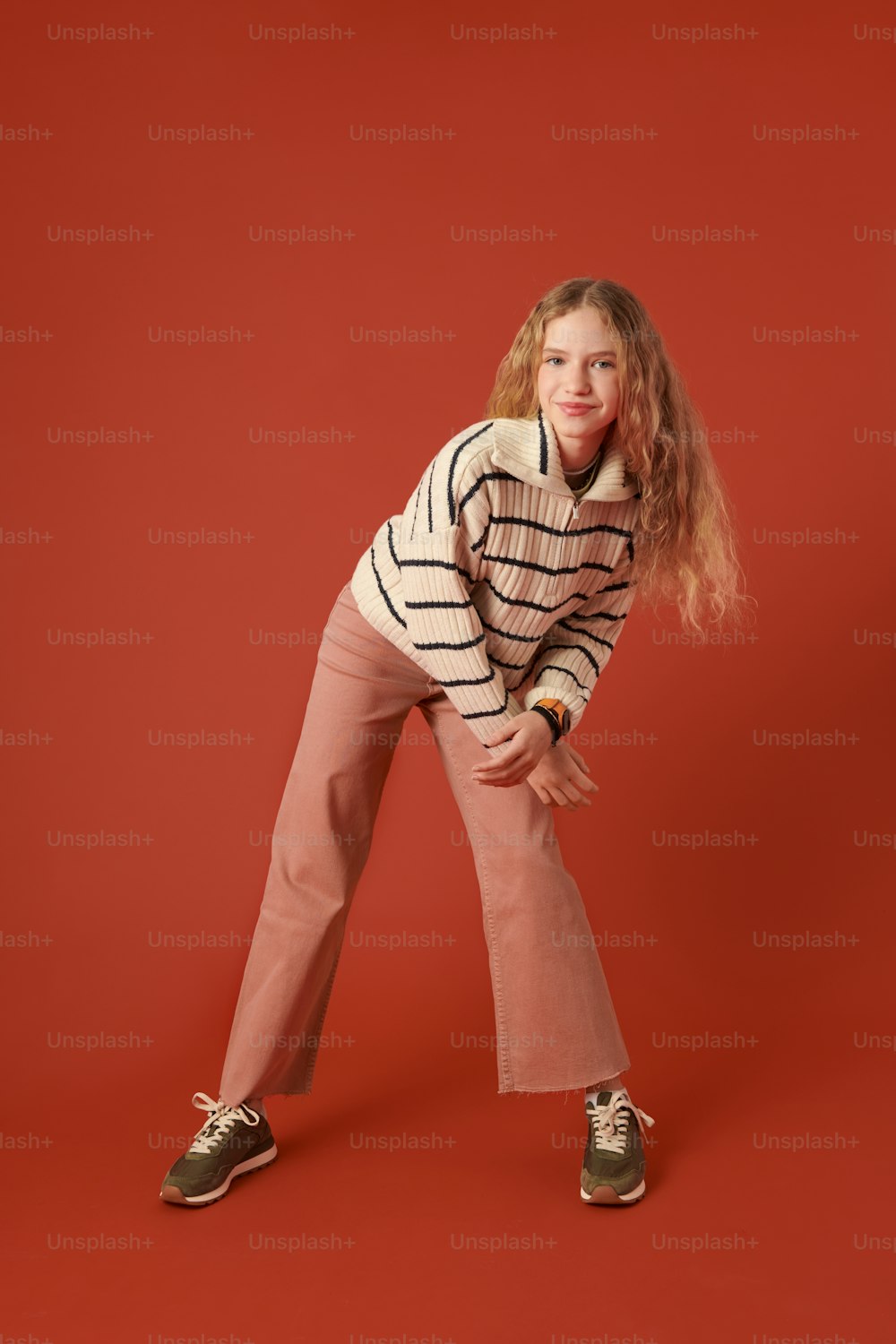 a young girl posing for a picture in front of a red background