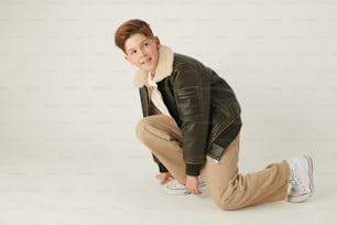 a boy in a black jacket and tan pants