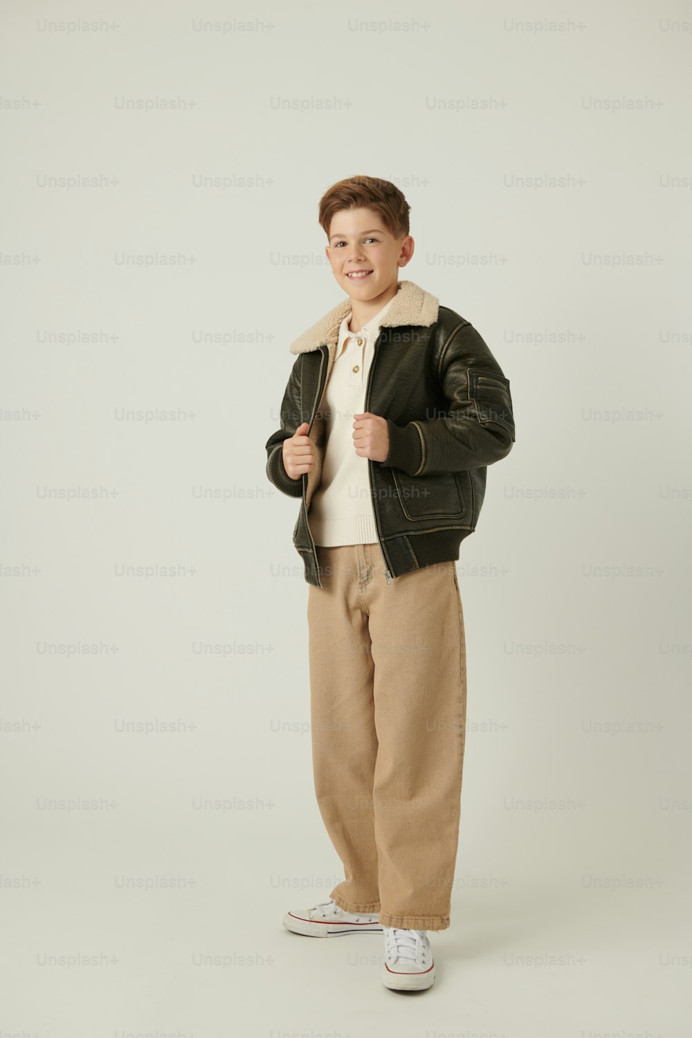 a young boy in a black jacket and khaki pants