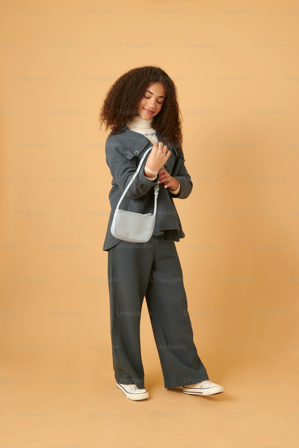 a woman in a gray suit and white sneakers