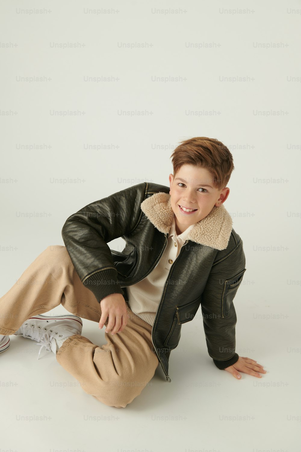 a young boy in a black jacket and tan pants