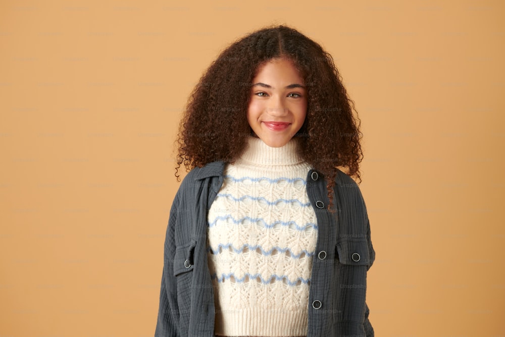 a woman with curly hair wearing a sweater and jacket