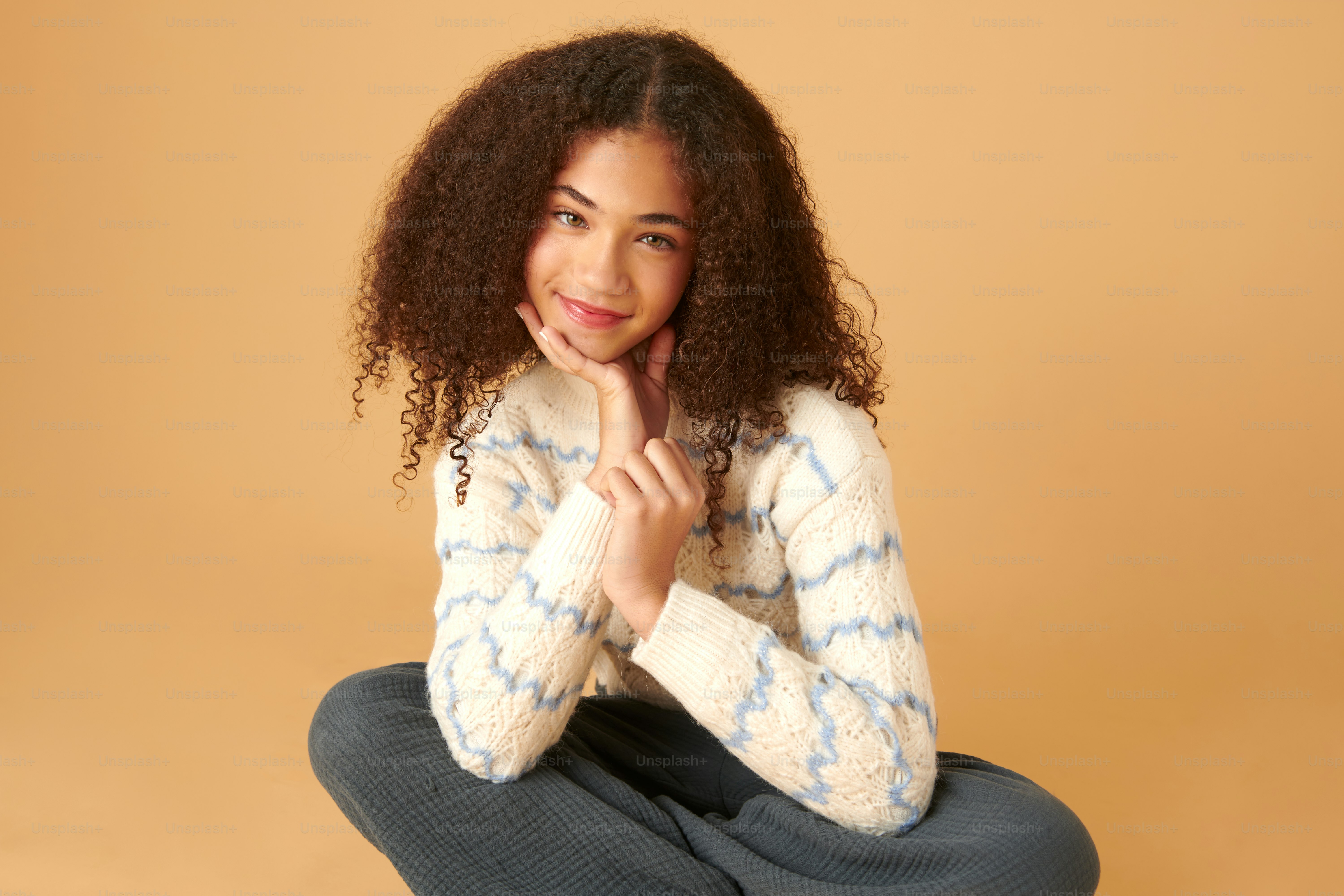 a woman sitting on the ground with her hands on her chin
