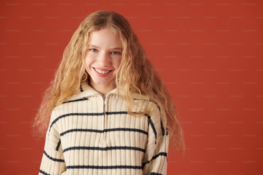 a young girl with blonde hair wearing a striped sweater