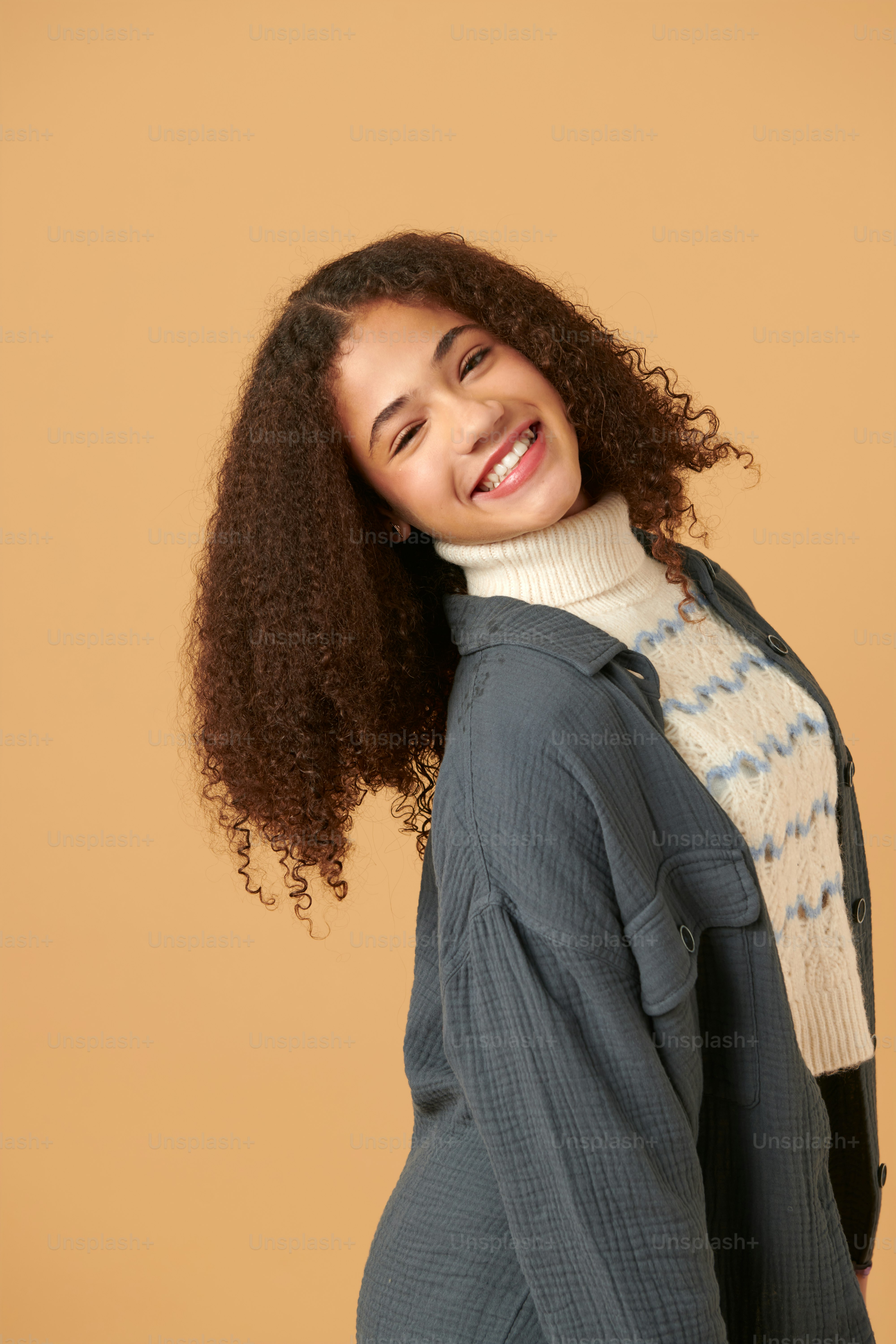 Une femme aux cheveux bouclés sourit à la caméra