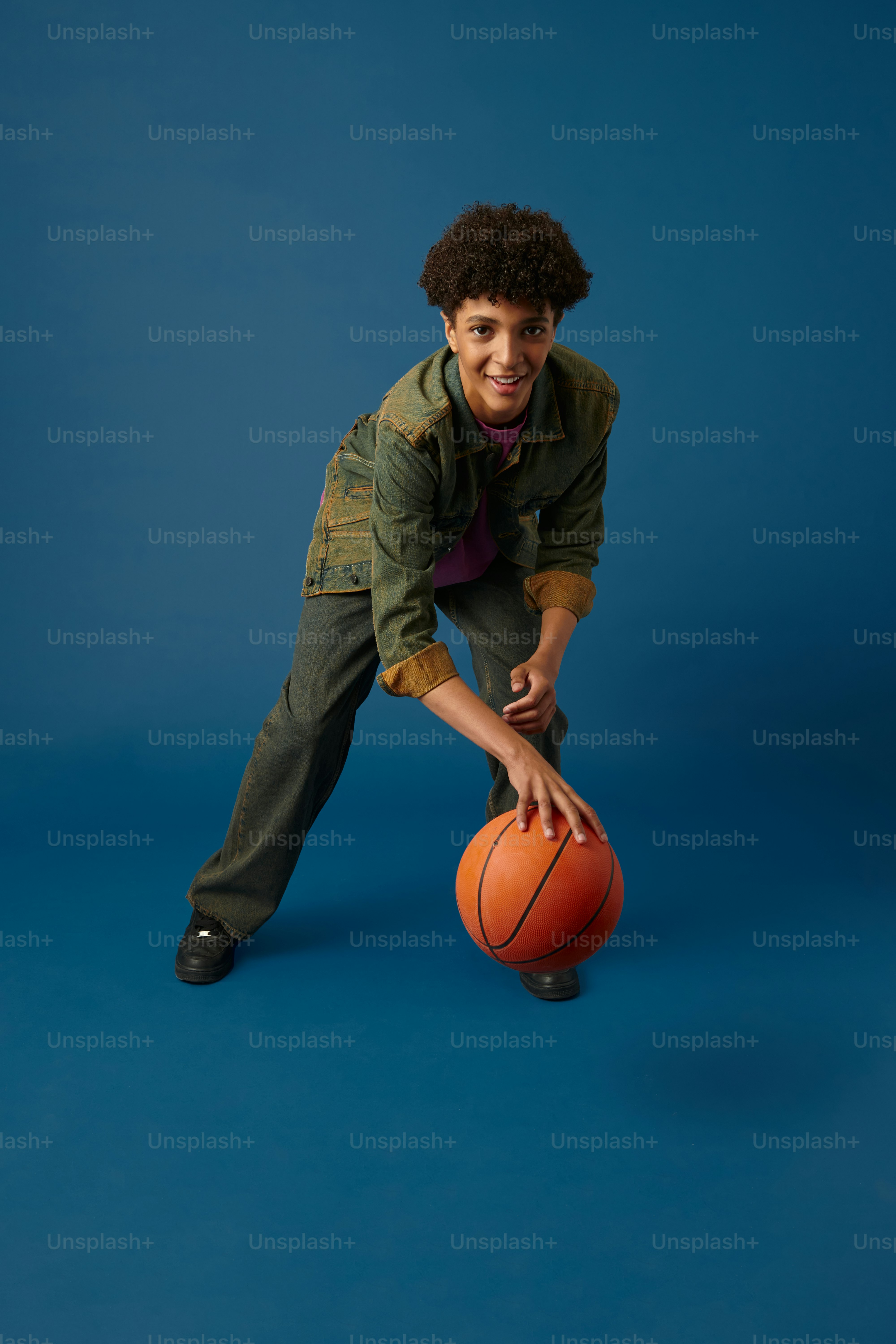 青い背景にバスケットボールを持つ若い男性