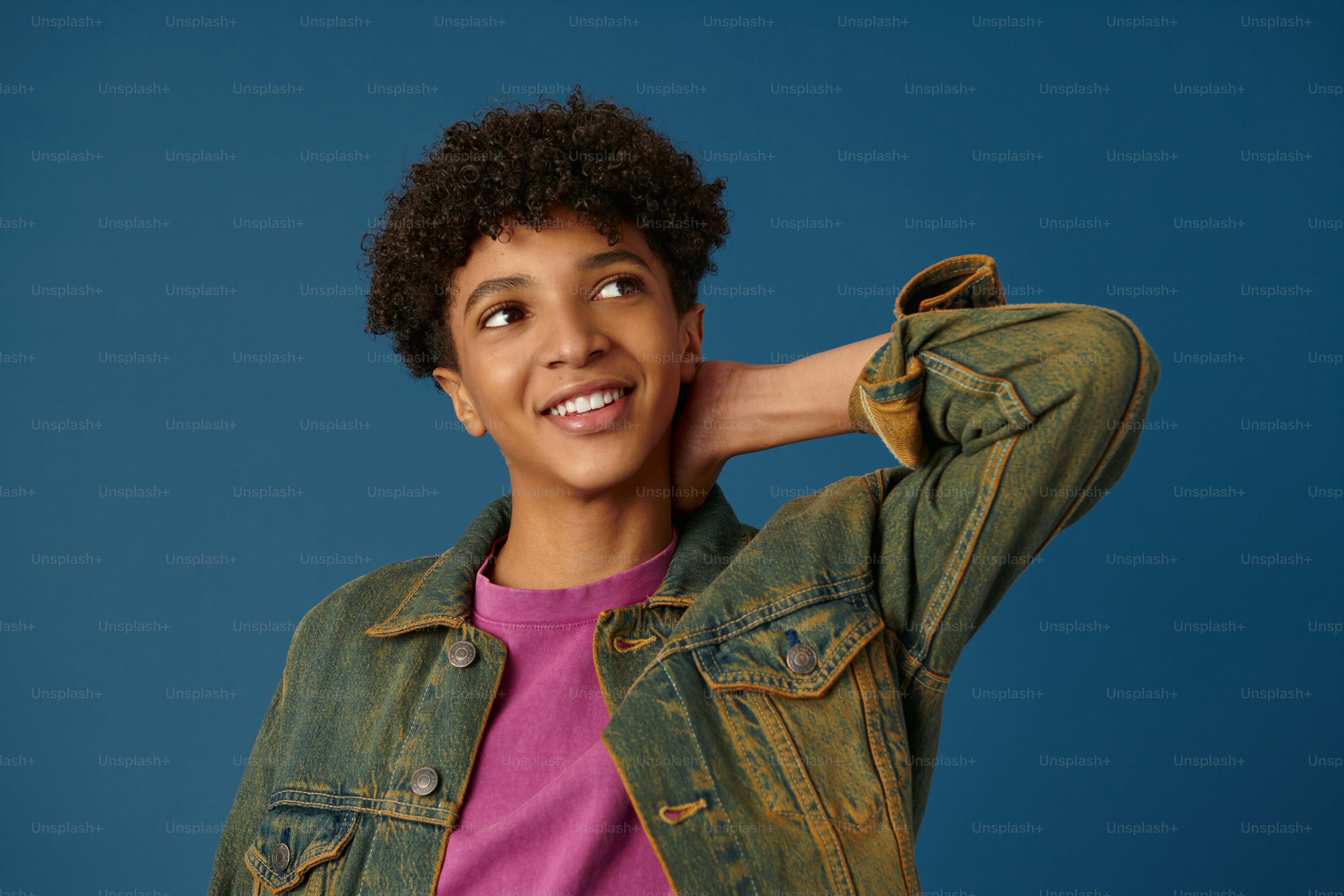 a young boy wearing a jean jacket and a pink shirt