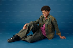 a young man sitting on the ground with his legs crossed