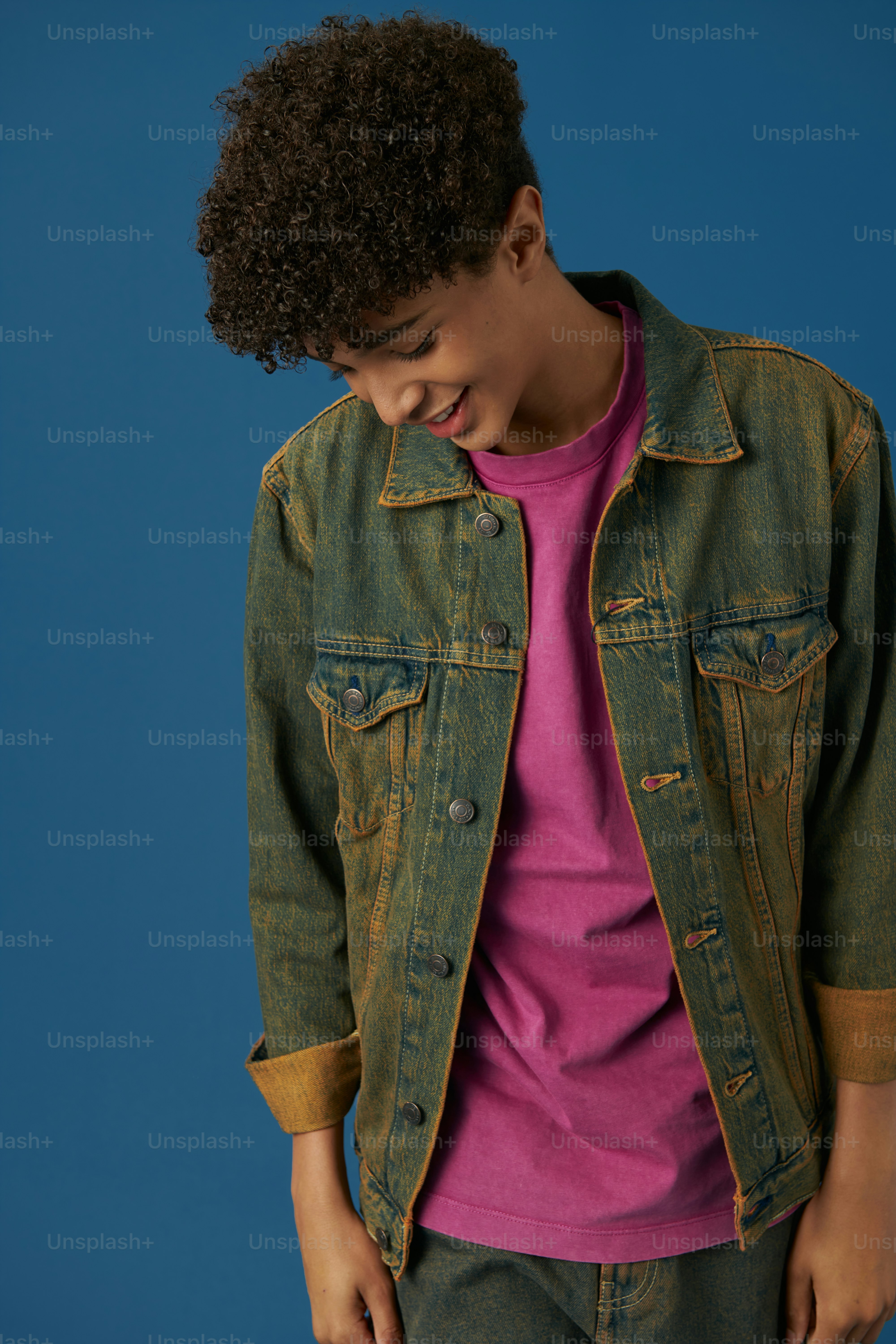 Un jeune homme vêtu d’une veste en jean et d’une chemise rose