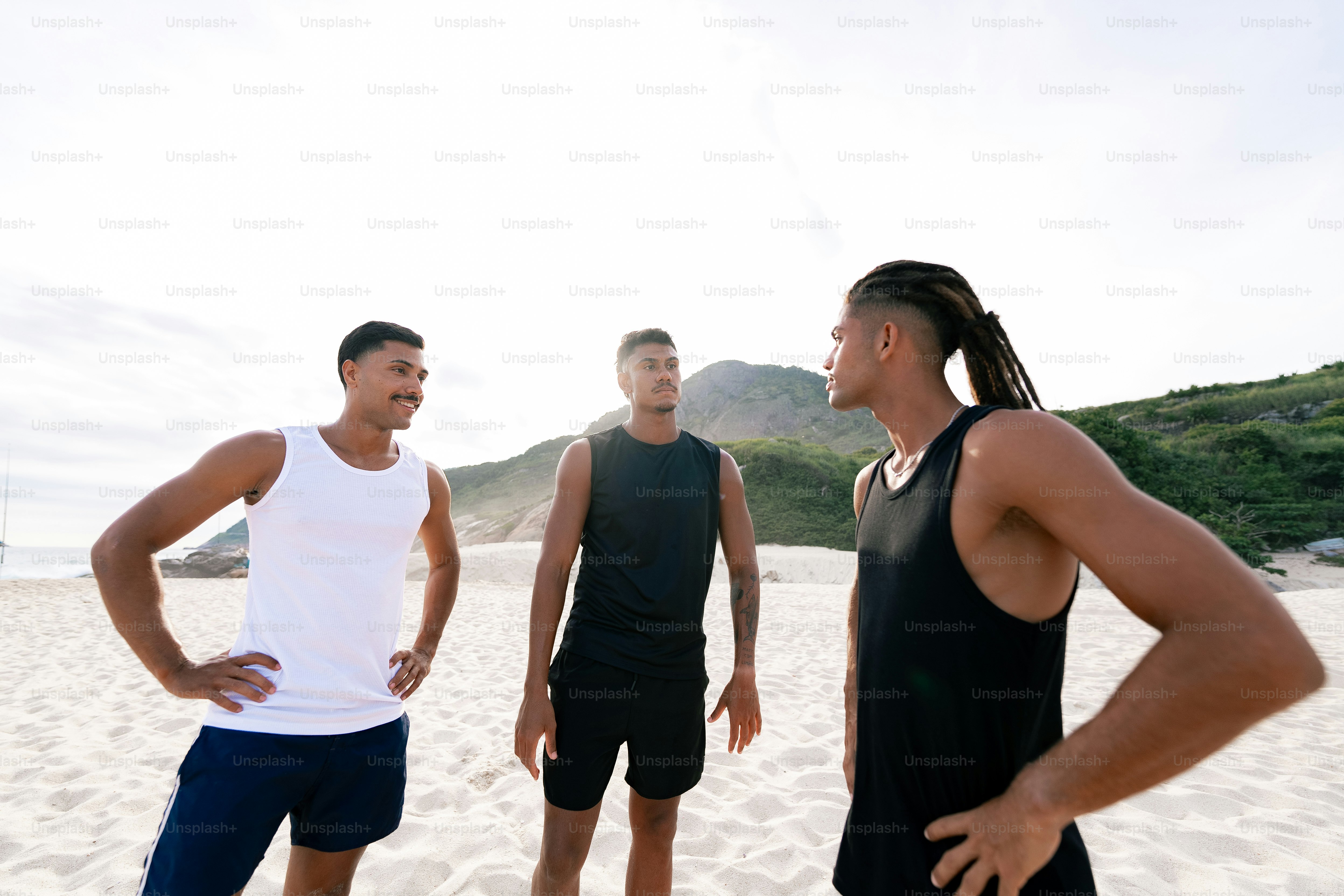 a group of men standing on top of a sandy beach