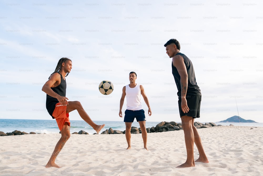 a group of people playing soccer on a beach