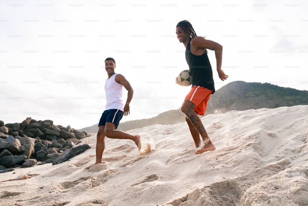 two men are playing soccer in the sand