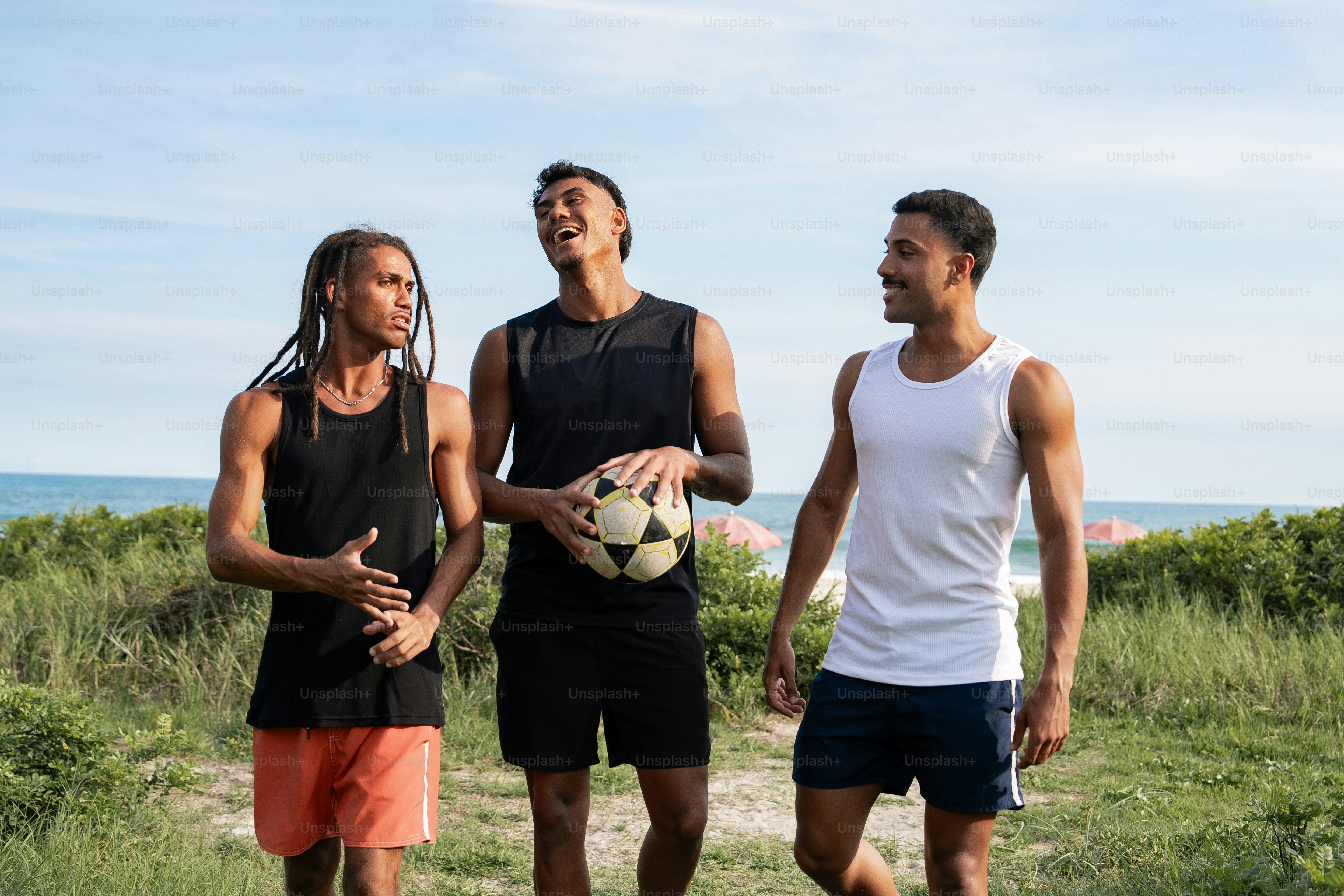 un gruppo di tre uomini in piedi uno accanto all'altro con in mano un pallone da calcio