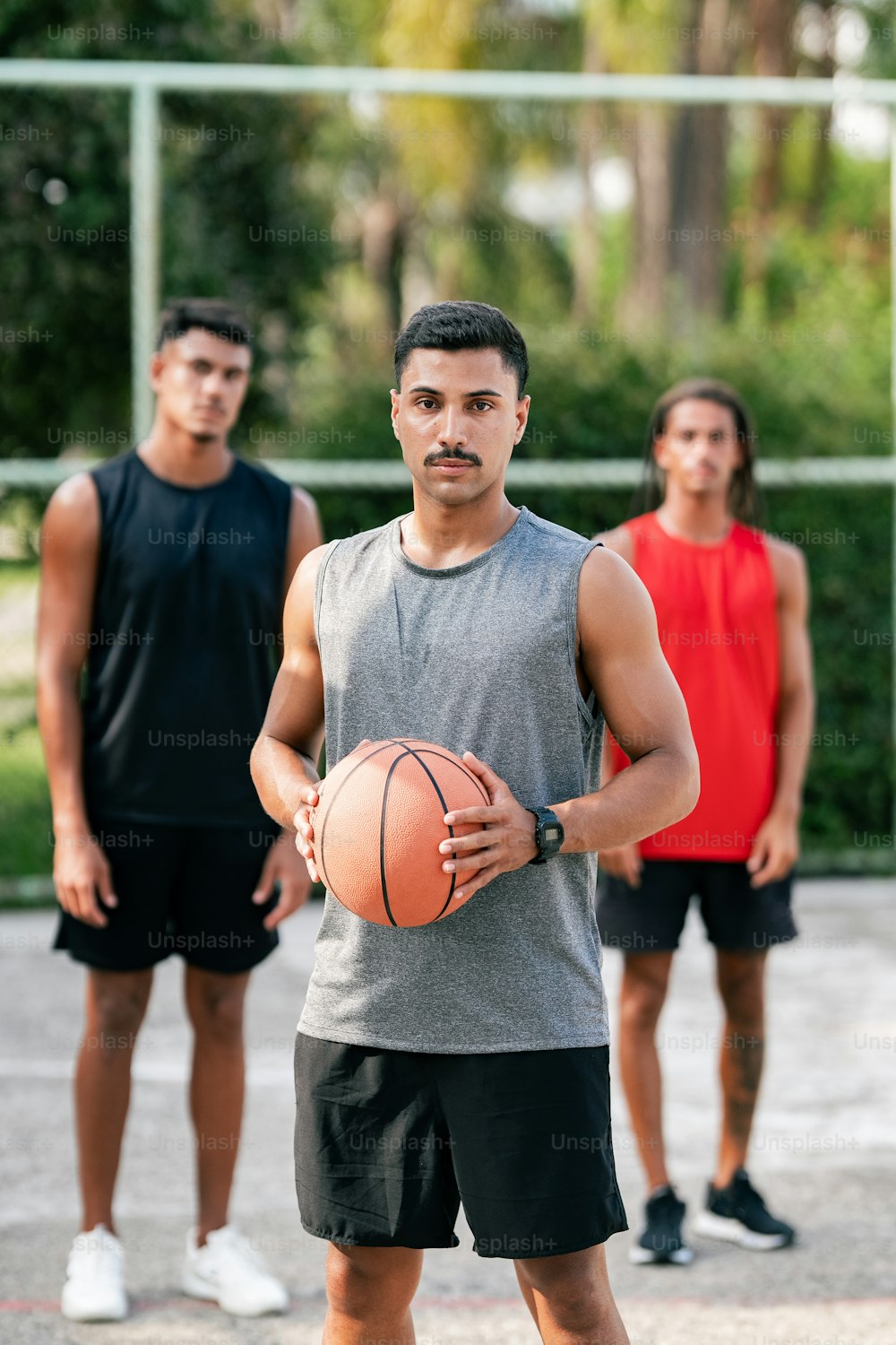 Un hombre sosteniendo una pelota de baloncesto frente a otros dos hombres