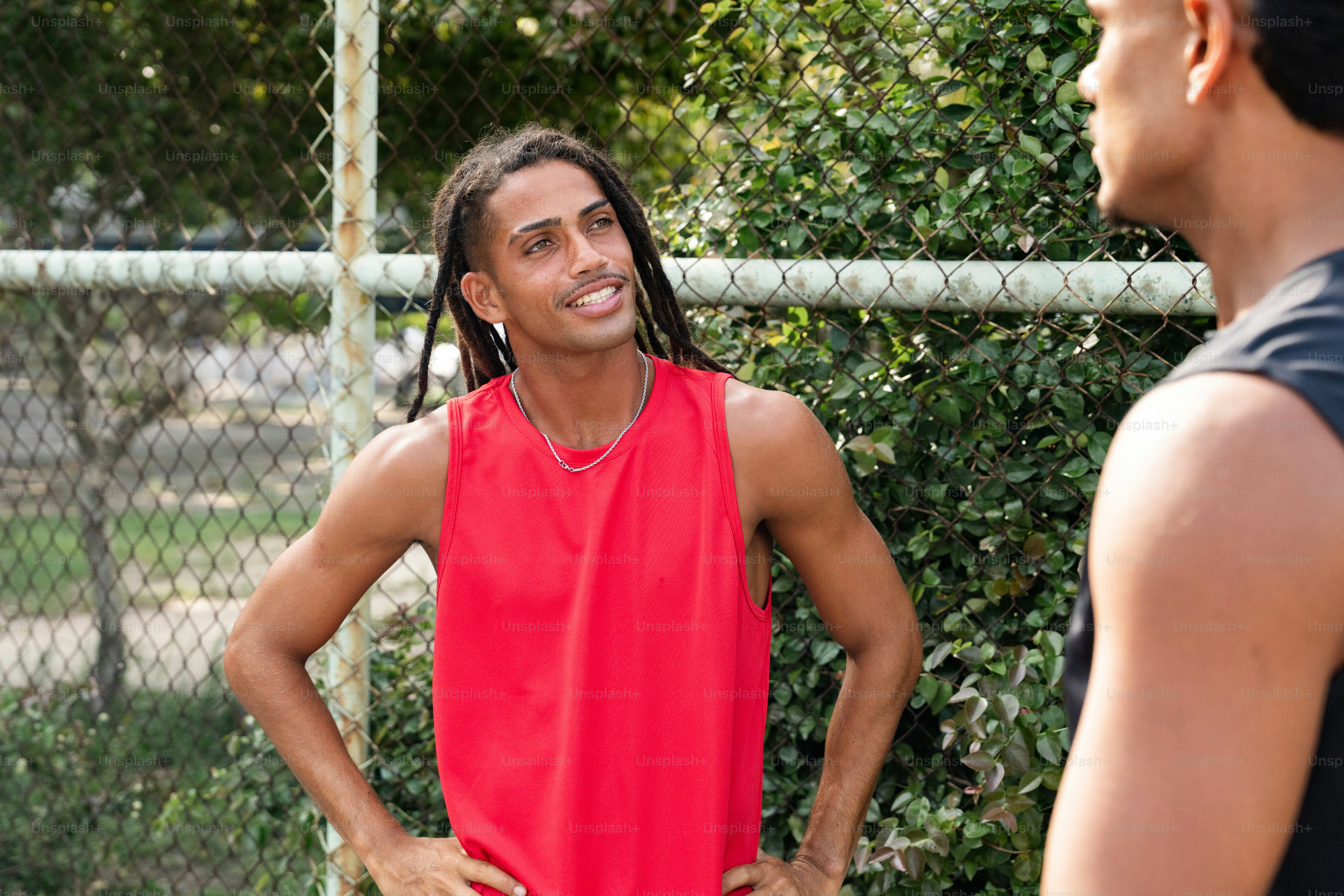a man standing in front of a fence with his hands on his hips