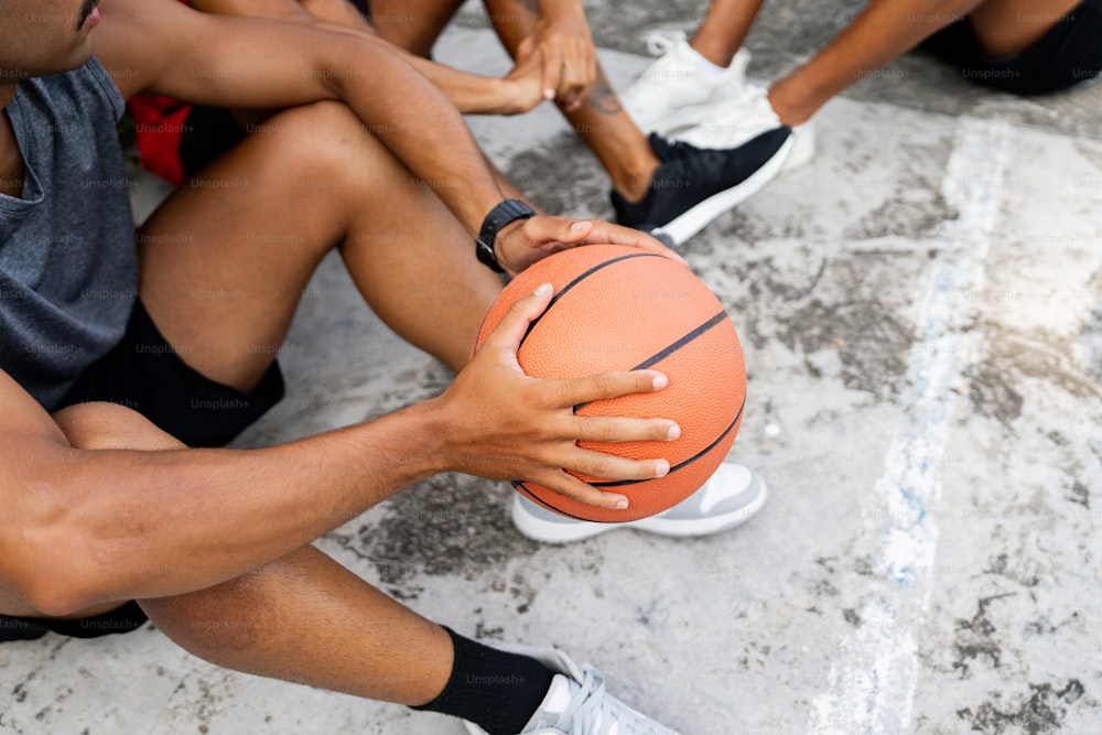 un grupo de personas sentadas en el suelo sosteniendo una pelota de baloncesto