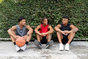 three men sitting next to each other with a basketball