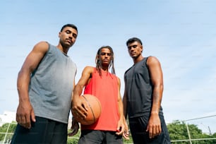 um grupo de três homens em pé um ao lado do outro segurando uma bola de basquete