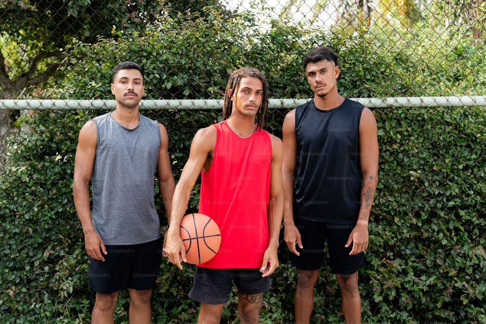 three men standing next to each other holding a basketball