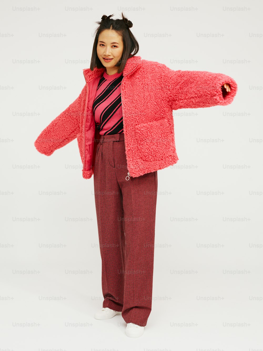 Una mujer con chaqueta rosa y pantalones rojos