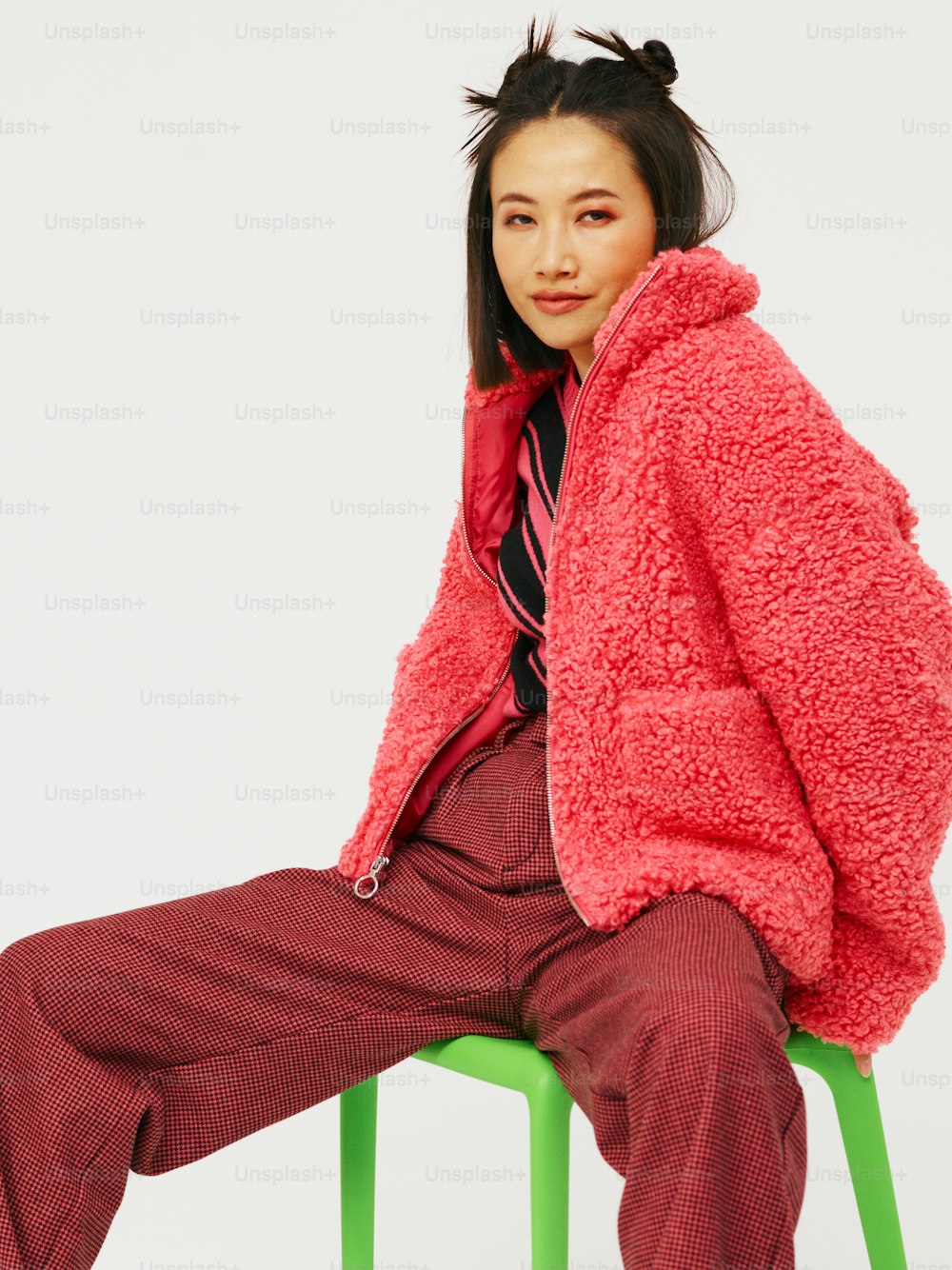 a woman sitting on a chair wearing a red jacket