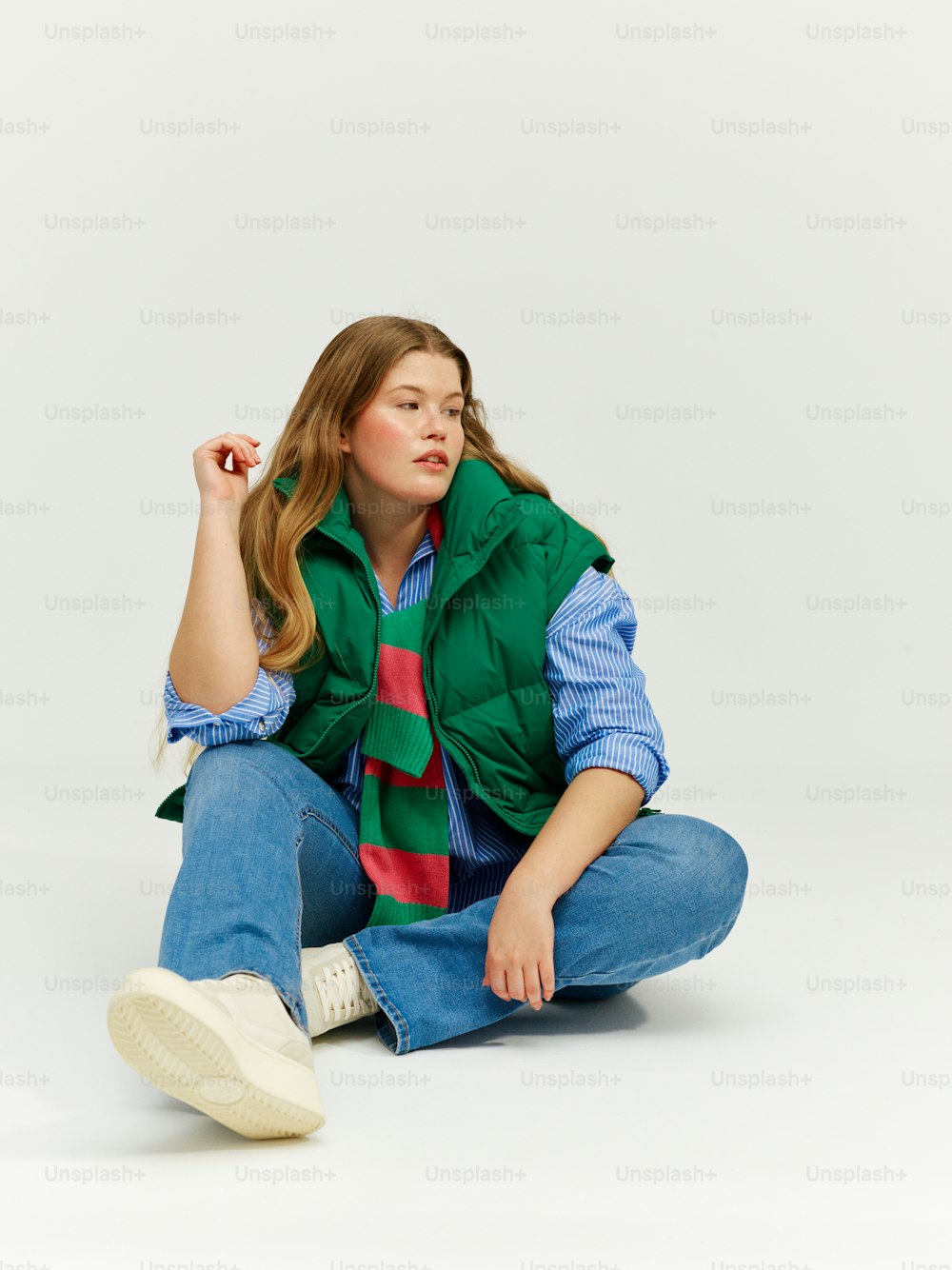 a woman sitting on the ground wearing a green vest