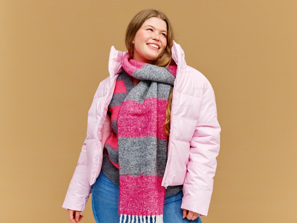 a woman wearing a pink jacket and a pink and grey scarf