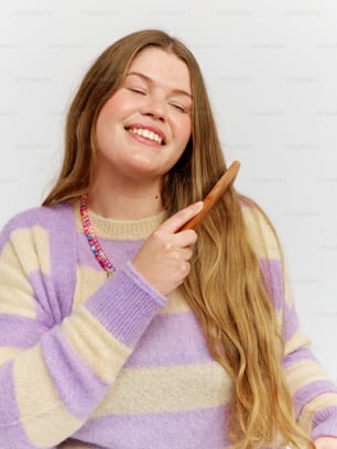 a woman is smiling while brushing her hair