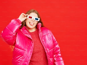 a woman wearing a pink jacket and red sweater holding a pair of 3d glasses