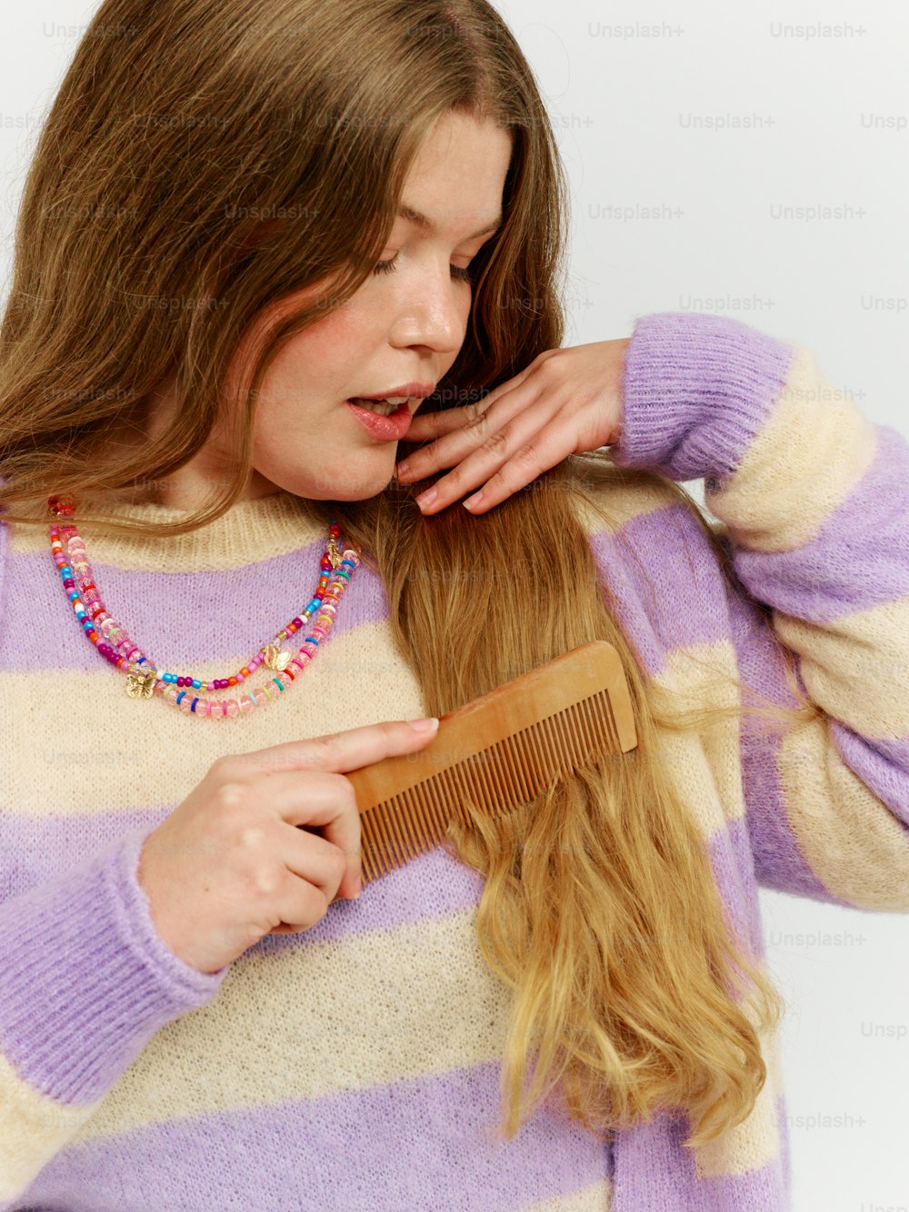 a woman combing her hair with a wooden comb