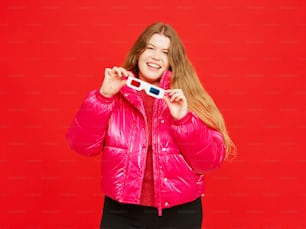a woman in a pink jacket holding a camera