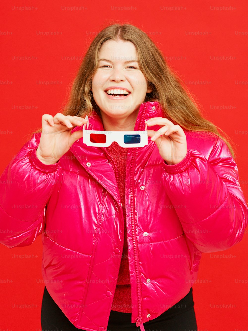 Eine Frau in einer rosa Jacke hält eine 3D-Brille hoch
