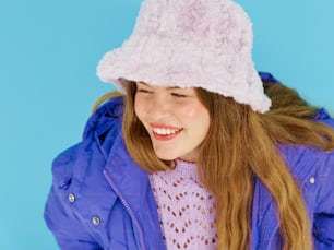 uma menina em uma jaqueta roxa e um chapéu rosa