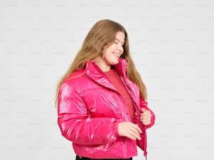 a woman wearing a pink jacket and black pants